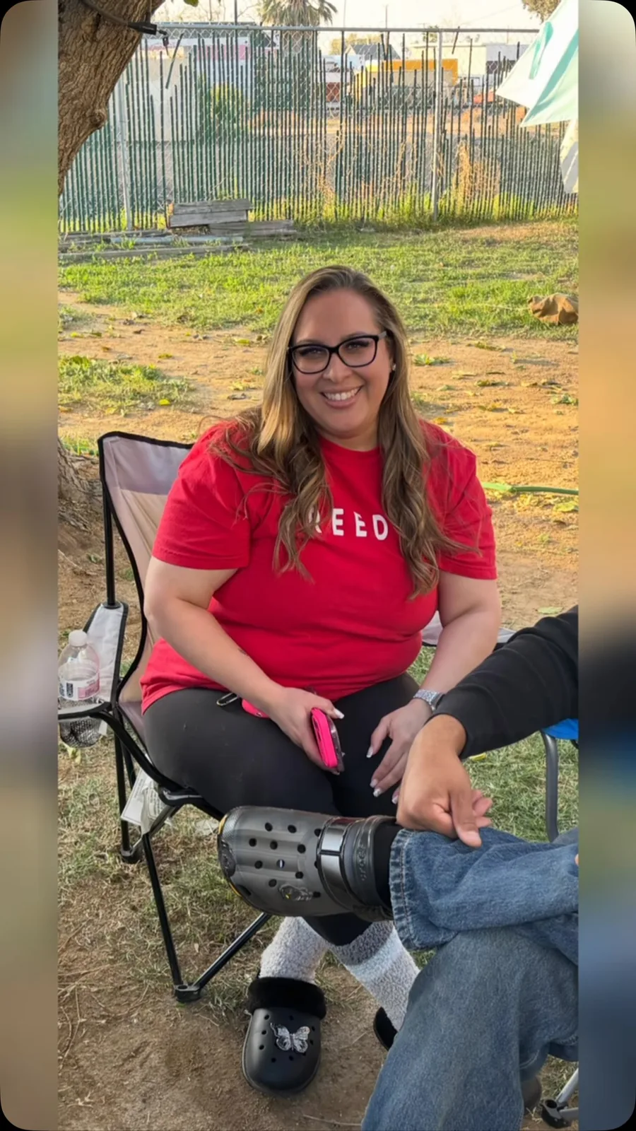 Heather smiling outdoors in a red shirt